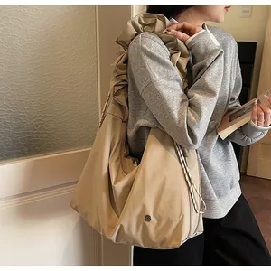 Detail of khaki pleated tote bag featuring wide straps and drawstring closure