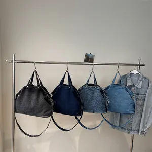 Large denim tote bags in four wash colors hanging on a rack with adjustable straps