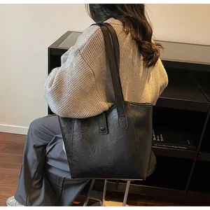 Close-up of matte black leather tote bag with wide straps and textured finish
