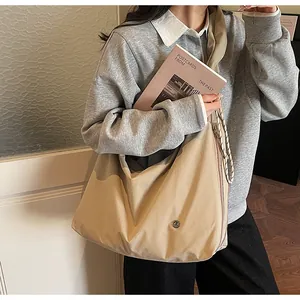 Detail of beige canvas tote bag with thick rope strap and circular metal logo accent