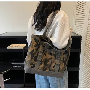 Detail of army green camouflage canvas tote bag with gray straps shown on model