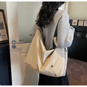 Detail of a large beige pleated tote bag with a wide shoulder strap worn by a model