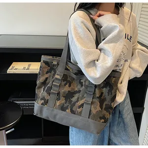 Detail of canvas tote bag showing camo print, gray handles, and side metal buckle