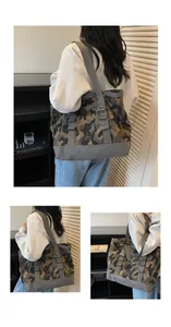 Detail view of the durable gray reinforced bottom and stitching on a camo canvas tote bag