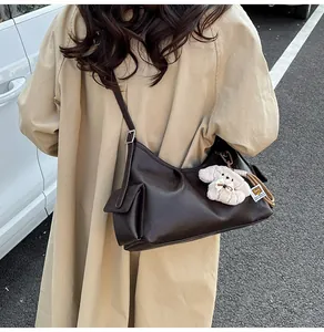 Detail of dark brown leather pillow bag with side pocket and plush dog charm