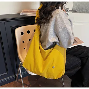Detail of large yellow pleated tote bag with silver logo buckle on wide shoulder strap