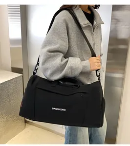 Détail du grand sac de voyage en tissu oxford noir porté par un mannequin avec logo