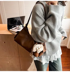 Detail view of a vintage brown pillow bag with a plush dog charm and a slim shoulder strap