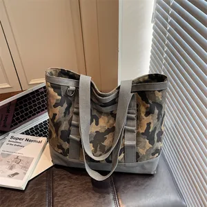 Minimalist camouflage canvas tote bag with gray straps on a stylish leather stool