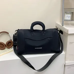 Détail du sac de voyage noir en tissu oxford avec étiquette latérale et bandoulière réglable