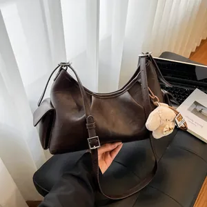 Deep brown matte faux leather pillow bag with adjustable strap and plush puppy charm