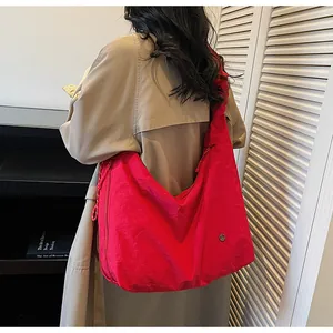 Detailed view of large bright red pleated tote bag worn as a shoulder bag