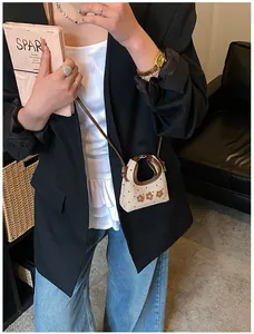Mini crossbody tas met beige textuur en bruine bloemborduurwerk getoond op model