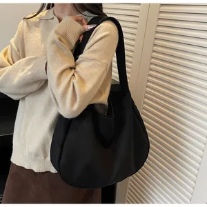 Detalle del bolso hobo negro minimalista mostrando el corte de media luna y la lona