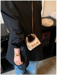 Detailopname van mini-tas in havermoutkleur met bruine stippen en bloemborduursel