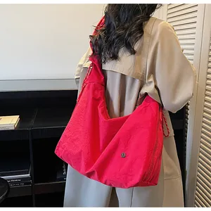 Detail of red nylon tote bag with drawstring strap and metallic logo on the side