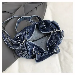 Dettaglio della borsa in denim lavato con rivetti metallici e trama retrò usurata
