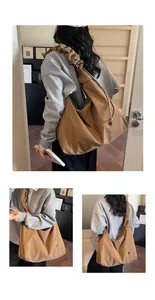 Detail of the brown tote bag featuring pleated wide straps and a functional side zipper