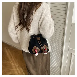 Vue détaillée d'un sac seau noir à cordon avec des sangles brunes et un charme tissé
