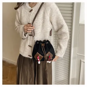 Détail du sac seau noir à cordon avec bordure marron et breloques festives en peluche