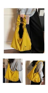 Close-up of bright yellow tote bag with ruched handles and circular metal emblem detail