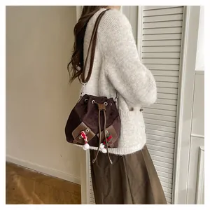 Détail du sac seau vintage marron avec fermeture à cordon et breloque de canne en sucre