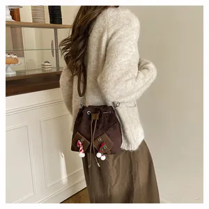 Détail d'un sac seau en daim marron foncé avec pompon festif et cordon de serrage