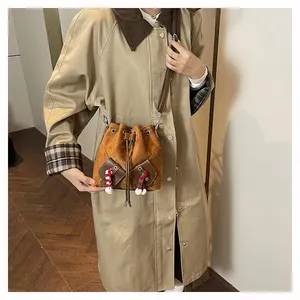 Détail du sac seau en daim marron avec cordon de serrage et petits ornements
