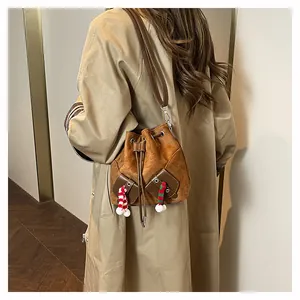 Détail d'un sac seau en daim marron avec écharpe festive et pompon blanc décoratif