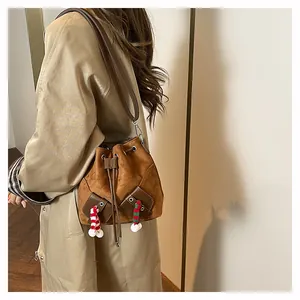Détail du sac seau vintage en daim marron avec des breloques pompons rayées décoratives