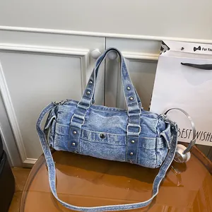 Borsa a cilindro in denim blu lavato con borchie argentate e tracolla regolabile