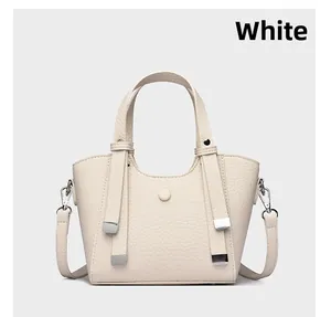 Gros plan sur la texture en cuir litchi blanc et les boucles métalliques du sac à main
