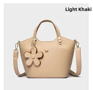 Detailed texture of light khaki bucket bag with floral charm and lychee grain finish