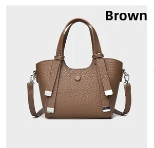 Détail de la texture cuir grainé marron et des ferrures argentées du sac à main