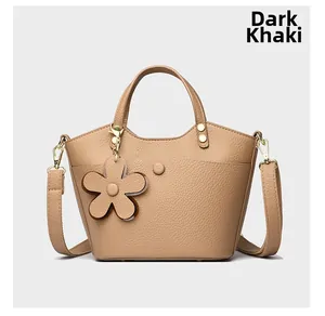 Detail of dark khaki bucket bag in litchi grain leather with flower pendant