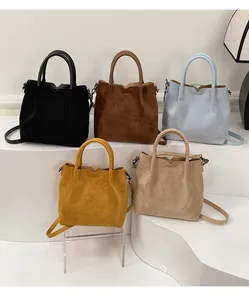Cinq coloris de sacs seau minimalistes en daim présentés sur des étagères élégantes