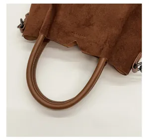Gros plan sur la texture en daim doux et les anneaux en métal du sac à main marron