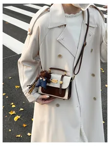 Detail of vintage patchwork crossbody bag with cute teddy bear charm and metal plate