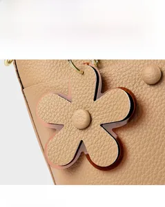 Close-up of lychee grain leather bucket bag featuring a decorative petal flower charm