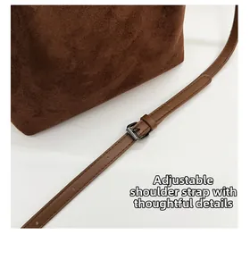 Détail du sac en daim marron foncé montrant la bandoulière réglable et la boucle en métal