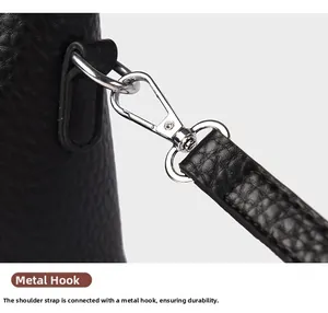 Détail du crochet en métal argenté fixé à la bandoulière en cuir noir à grain de litchi