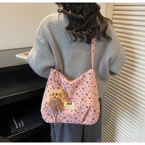 Détail du sac bandoulière en velours côtelé rose avec motifs cœurs et breloque ours