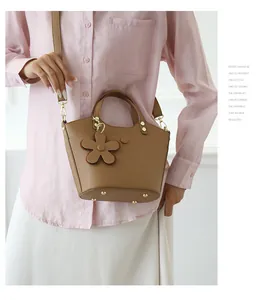 Detail of brown lychee grain leather bucket bag with flower charm and metal studs