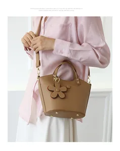 Brown litchi leather bucket bag detail with flower charm and golden bottom rivets