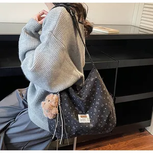 Détail du sac cabas en toile noire avec motifs nœuds et charmant pendentif ours brun