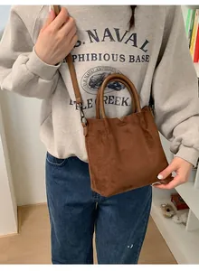 Sac bandoulière en daim marron avec sangle réglable et quincaillerie vintage sur modèle