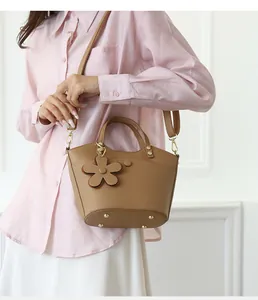 Close-up of caramel leather bucket bag with flower charm and metallic base studs