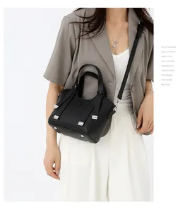 Détail d'un sac à main noir en cuir grainé avec finitions argentées sur un blazer gris