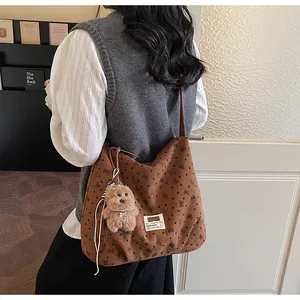 Sac à bandoulière en velours côtelé marron avec motifs nœuds porté par un modèle