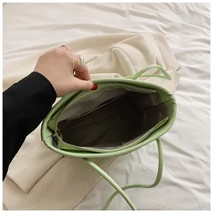 Detailed interior of green pleated tote bag with zipper closure and gray lining